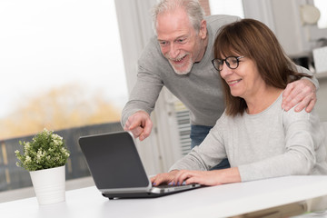 Happy mature couple having a good surprise on laptop