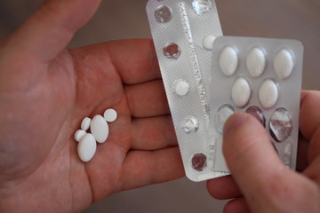 Male hand holding pills and two blister pack.
