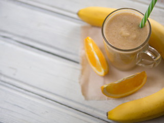 fresh summer milkshake or orange and banana smoothie on wooden white table. top view