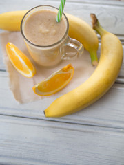 fresh summer milkshake or orange and banana smoothie on wooden white table. top view