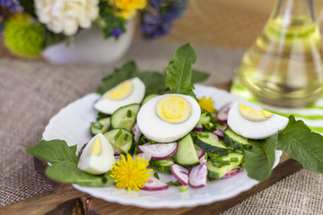 salad of dandelions, Healthy spring salad of young leaves of dandelion, cucumber, radish and egg on a plate closeup