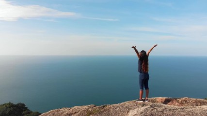 Woman with arms on top of mountain looking at Sunset view Hiker Girl lifting arm up celebrating life scenic nature landscape enjoying vacation travel adventure
