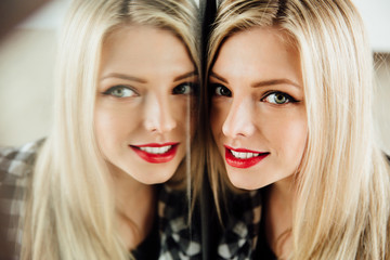 portrait of beautiful young woman blonde girl and her reflection in mirror.