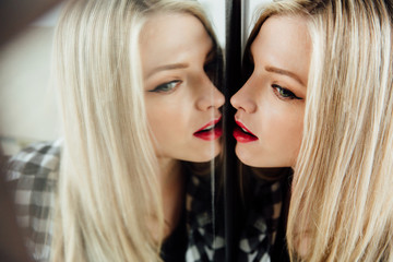 portrait of beautiful young woman blonde girl and her reflection in mirror.