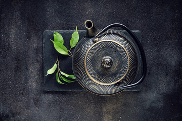 Grünteeblatt mit schwarzer Teekanne
