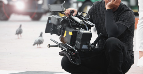 Blurred images of high definition video camera and lens on steady equipment support such as gimbal steady or stabilized shoulder rig and pan tilt shift head tripod for handheld filming moving object. © gnepphoto