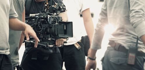 Blurred images of high definition video camera and lens on steady equipment support such as gimbal steady or stabilized shoulder rig and pan tilt shift head tripod for handheld filming moving object.