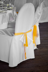 White chairs with covers with yellow ribbon, wedding decor