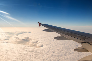 Obraz premium Wing of airplane in with sunrise and blue sky.