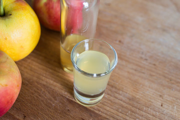 immune defense boosting, skin clarifying, detoxing apple cider vinegar on wooden table with ripe apples as decoration