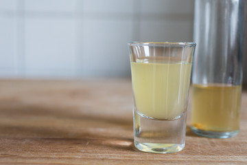 a glass and bottle with clarifying, detoxing apple cider vinegar for health benefits on wooden table