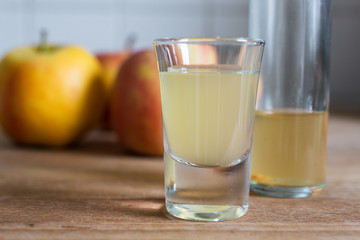 a glass of healthy cloudy fermented apple cider vinegar with apples as decoration on wooden table
