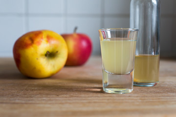 bottle and glass filled with naturally cloudy apple cider vinegar with apples as decoration on wooden table