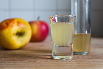 immune defense boosting, skin clarifying, detoxing apple cider vinegar on wooden table with ripe apples as decoration