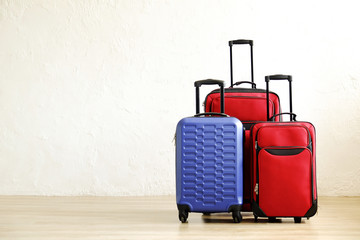 Three suitcases of different size, big & small, red textile and blue hard shell luggage with extended telescopic handle. Family trip concept. Copy space, white wall background. Fully packed baggage.