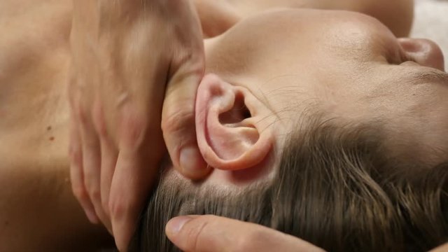 head massage at spa center. client enjoys the services of a massage therapist