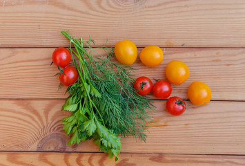 Dill and cherry tomatoes on wooden background.