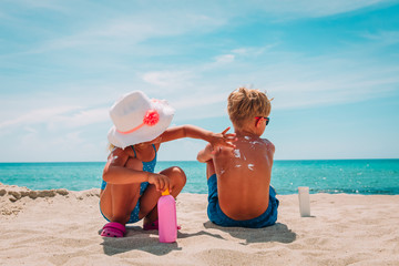 sun protection, little girl applying sunblock cream on boy shoulder - 213227835