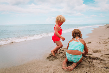 little girls play with sand at beach