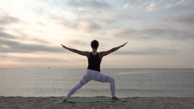 Woman practicing yoga on the beach. Outdoors sports. Healthy living.
