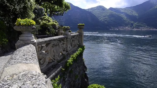 View of Como lake with botanical green garden with mountain hill in the background