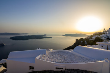 Incredibly romantic scene on Santorini. Fira, Greece. Amazing sunset view towards the deep sea crystal waters with white house roofs with pebbles terrace