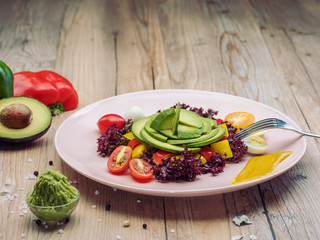 Dietary avocado salad with cherry tomatoes, quail eggs, yellow and red pepper and lettuce. Avocado is source of nutrition, vitamins, popular food product for sport and health diet. 