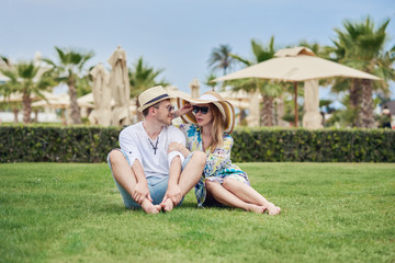 Fototapeta premium Caucasian couple of tourists spending time on a green lawn at sea resort.
