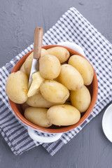 Young boiled potatoes with butter in a cup. Towel and gray background. Delicious vitamin summer dinner. Copy space.
