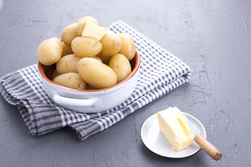 Young boiled potatoes with butter in a cup. Towel and gray background. Delicious vitamin summer dinner. Copy space.