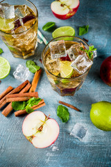 Spicy cinnamon apple iced tea or lemonade cocktail, summer refreshment drink, blue background copy space