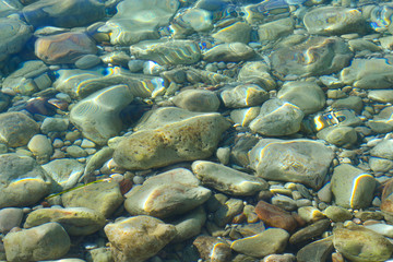 Marine background. Quiet Adriatic Sea. Blue clear water and large stones.