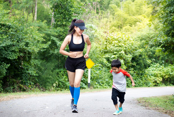 Mother and son jogging on the road In the forest.wide angle copy space image.
