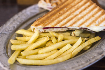 Triangular toast with cheese and ham on an old tin plate with French fries