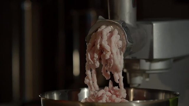 Process of making minced meat by modern automatic machine in kitchen. Flows of forcemeat are falling in metal cup, front view