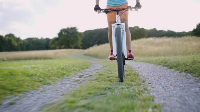 4K woman cycling down on electric mountain bike in rural landscape
