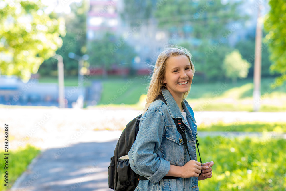 Wall mural a teenage girl. in the summer in park. behind the backpack. concept soon to school. free space for t