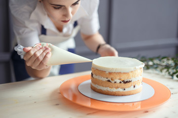 confectioner in a white apron on a dark background with a cake