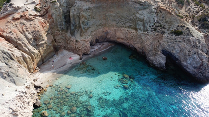 Aerial drone bird's eye view of iconic volcanic white chalk beach and caves of Tsigrado with turquoise and sapphire clear waters, Milos island, Cyclades, Greece