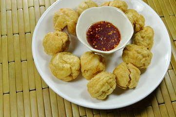 crispy fried fish ball dipping with spicy and sweet sauce cup on plate