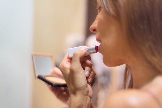Beautiful Woman close up applying lipstick