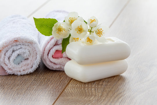 White towels and soap for bathroom procedures and flowers of jasmine on wooden boards