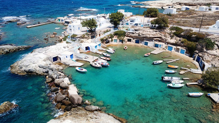 Obraz premium Aerial drone bird's eye view photo of picturesque small fishing harbor of Mandrakia with boat houses called syrmata and fishing boats docked on turquoise clear waters, Milos island, Cyclades, Greece