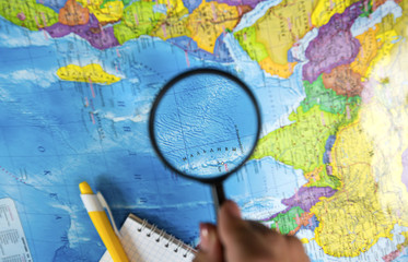 Fototapeta na wymiar Search for new bright places to travel on the map and looking at the magnifying glass