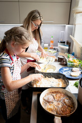 Mum and daughter busy in the kitchen preparing cooking dinner