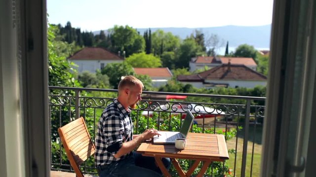 freelancer working behind a laptop on the balcony overlooking the resort town