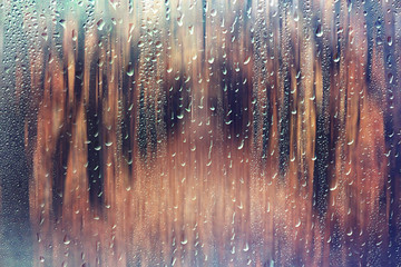 glass wet autumn background, rain in the park glass wet surface with reflection, rain drops on the drenched window glass, background window in the autumn park, autumnal rainy landscape blurred