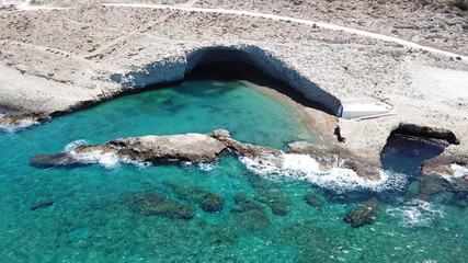 Aerial drone bird's eye view photo of volcanic cove of Alogomandra with turquoise clear waters and white rock, cave formations, Milos island, Cyclades, Greece