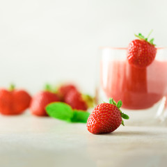 Bottle with vegan strawberry smoothie on grey background with copy space. Square crop. Summer food and clean eating concept, vegan diet. Pink detox beverage with fresh berries