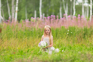 Fototapeta na wymiar Little blonde girl picking up flowers on meadow